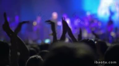 歌手在大批兴奋的观众面前表演，随着灯光的下降，他们的掌声停止了